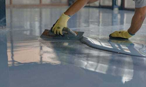 5-Epoxy-Flooring-in-Irvine,-CA man adds coating to floor